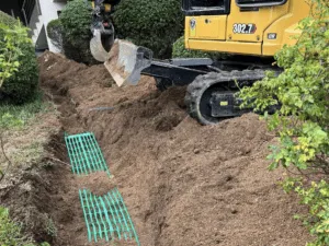 Mini-pelle et drains posés dans une tranchée de jardin à Porticcio