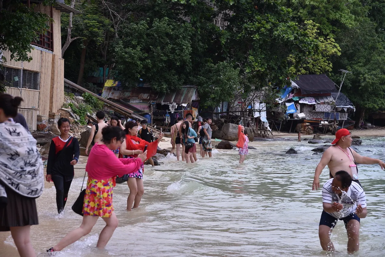 Chinese tourists frolicking on the beach, taking selfies of each other in Koh Phi Phi