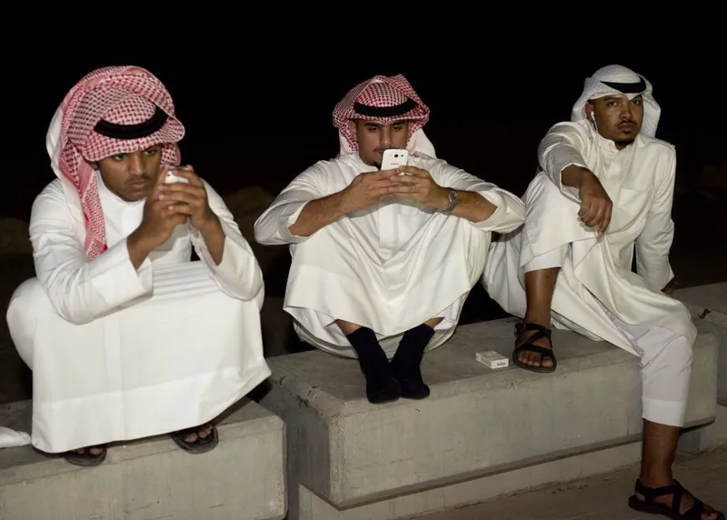 Kuwaiti men look at their cell phones