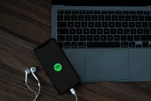 A mobile phone with the Spotify logo, near a MacBook Pro.