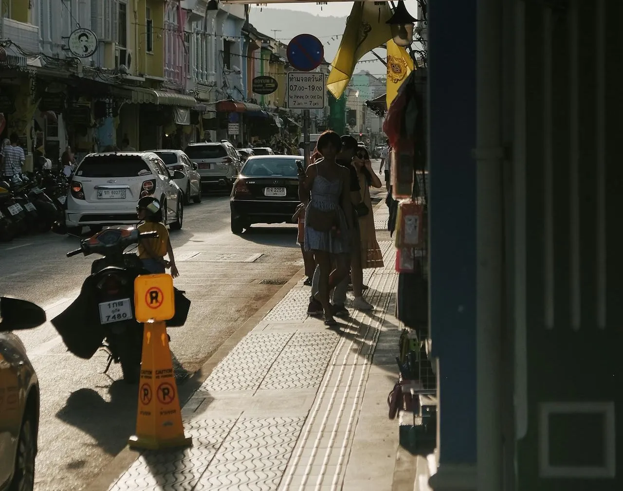 People walking on the sidewalk on a street in Rawai, Phuket.