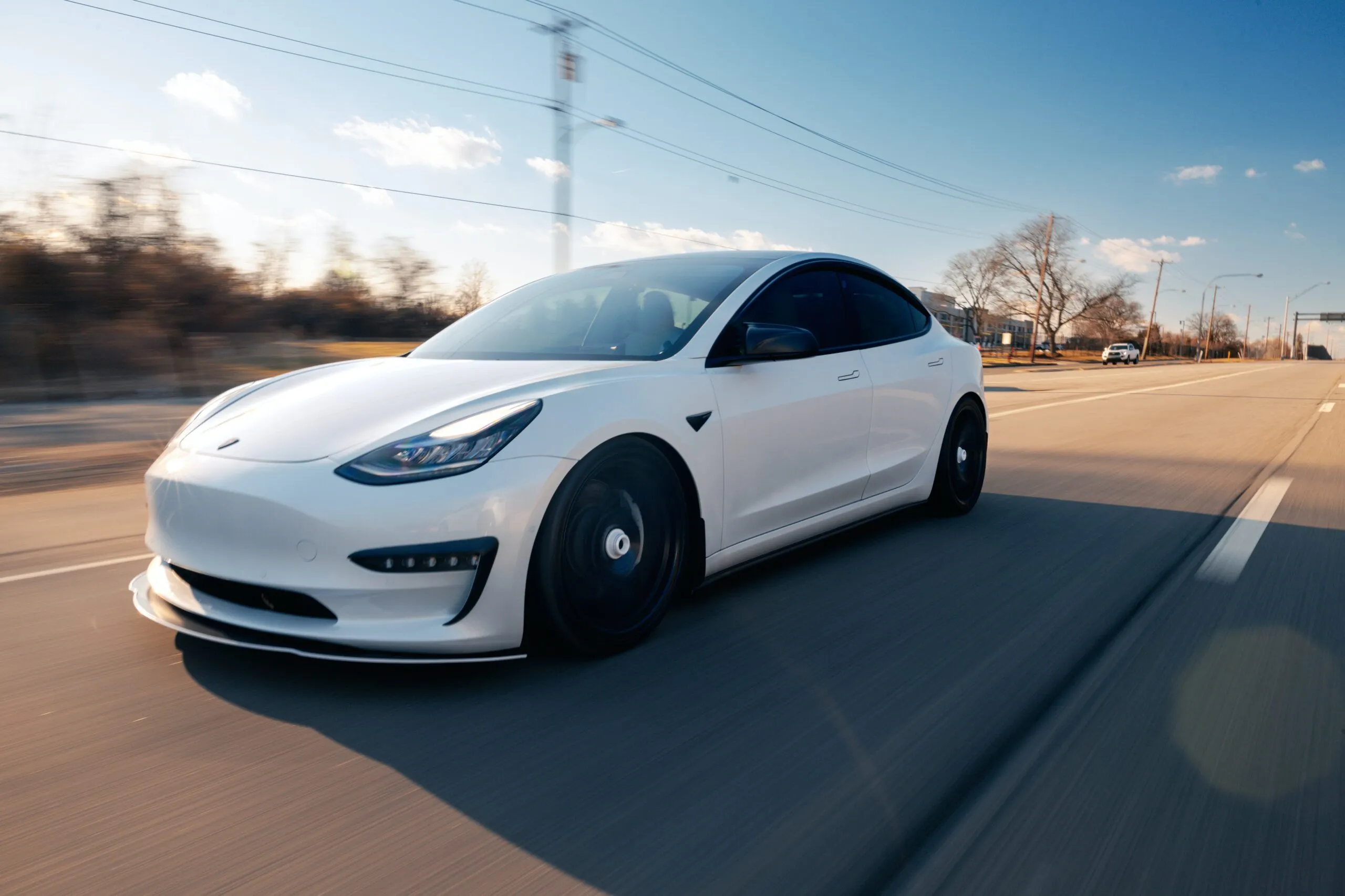 White Tesla EV car Driving on the Road