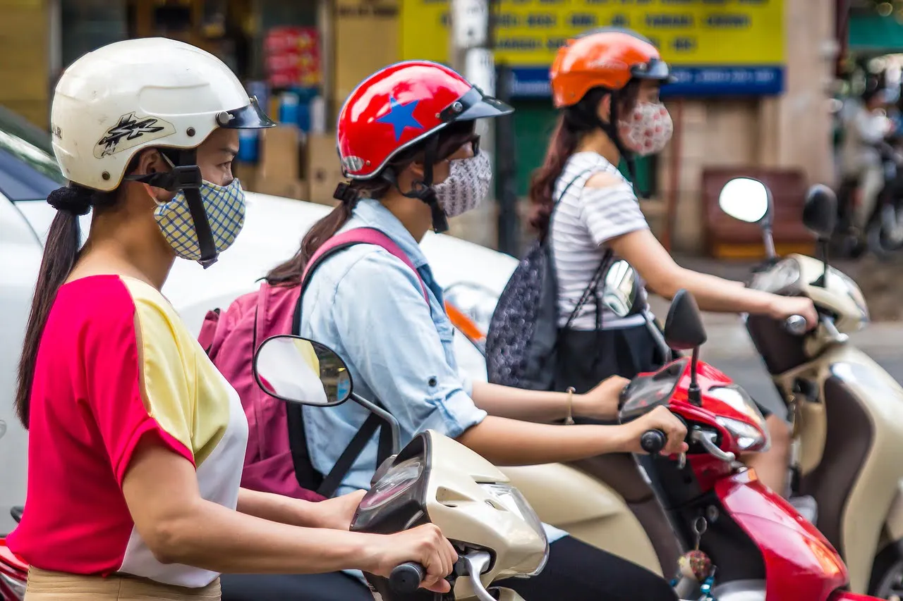 Girls wearing face masks riding scooters in Hanoi