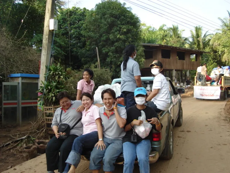 People sitting down on the back of a pick up in Laplae