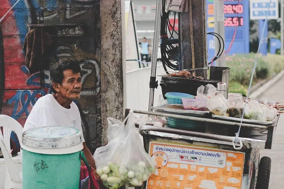 Food vendor sitting down behind a food stall