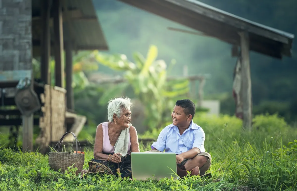 Thai grandmother and grandson using a laptop outdoors