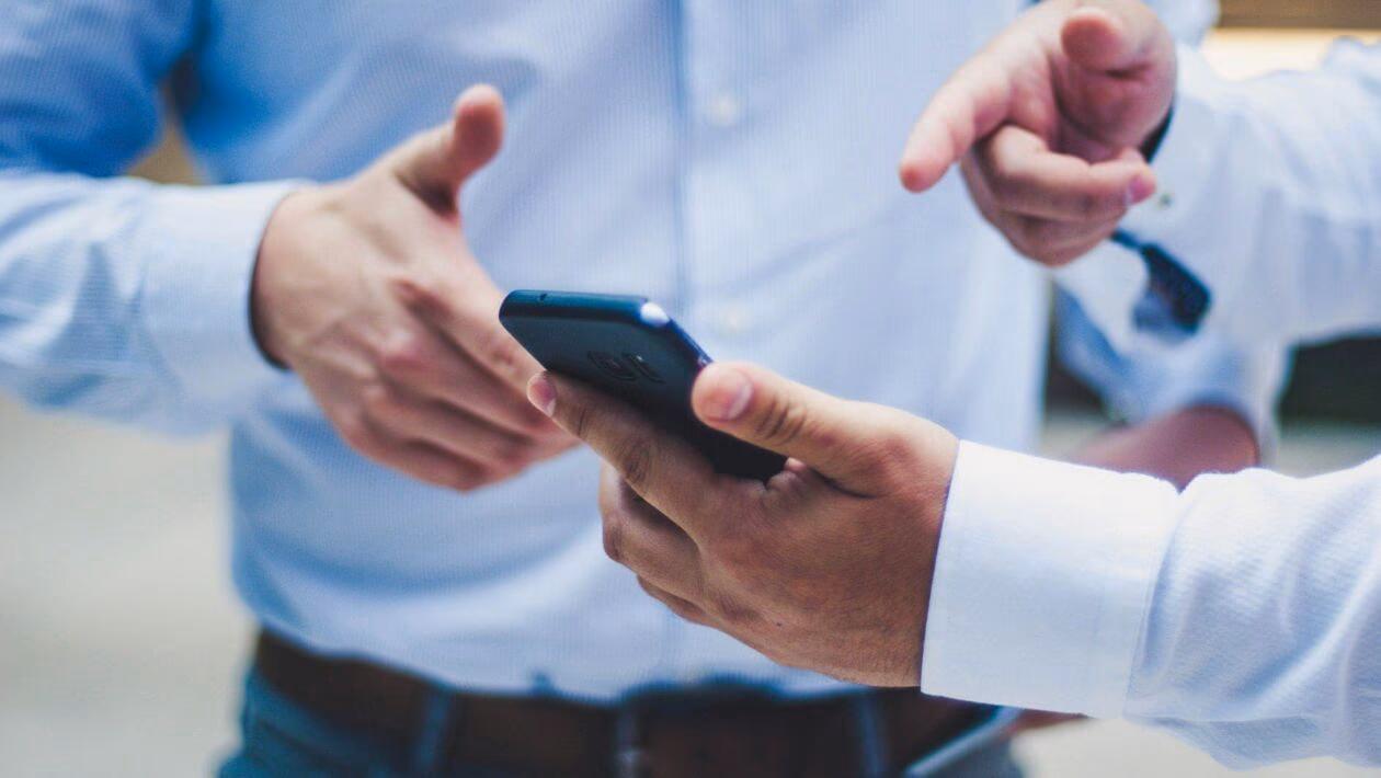 Telefon im Austausch bei einem geschäftlichen Treffen, modernes Kommunikationstechnologie, Business-Meeting, professionelle Zusammenarbeit, Hände halten Smartphone.