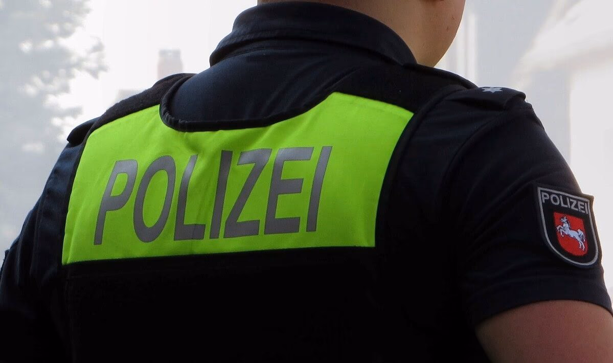 Polizeibeamter bei einer Durchsuchung im Rahmen eines Betrugsverdachts, Polizei in Deutschland, Einsatzkräfte bei Ermittlungen, Sicherheitsmaßnahmen, Polizeiuniform, Polizeiweste mit "POLIZEI" Schrift.